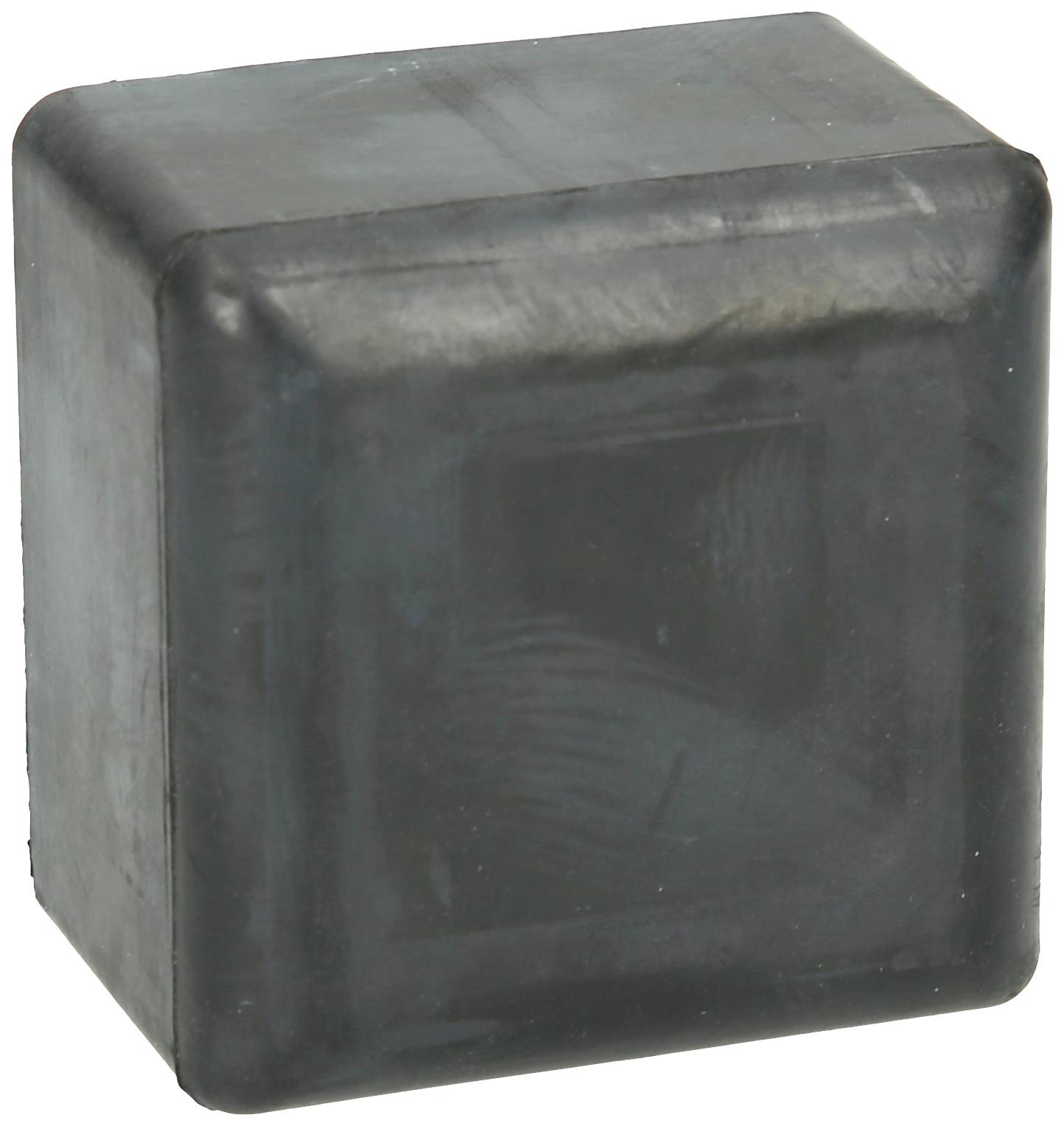 Ein schwarzer, rechteckiger Gummiwürfel mit leicht abgenutzter Oberfläche steht auf einer hellen Fläche.