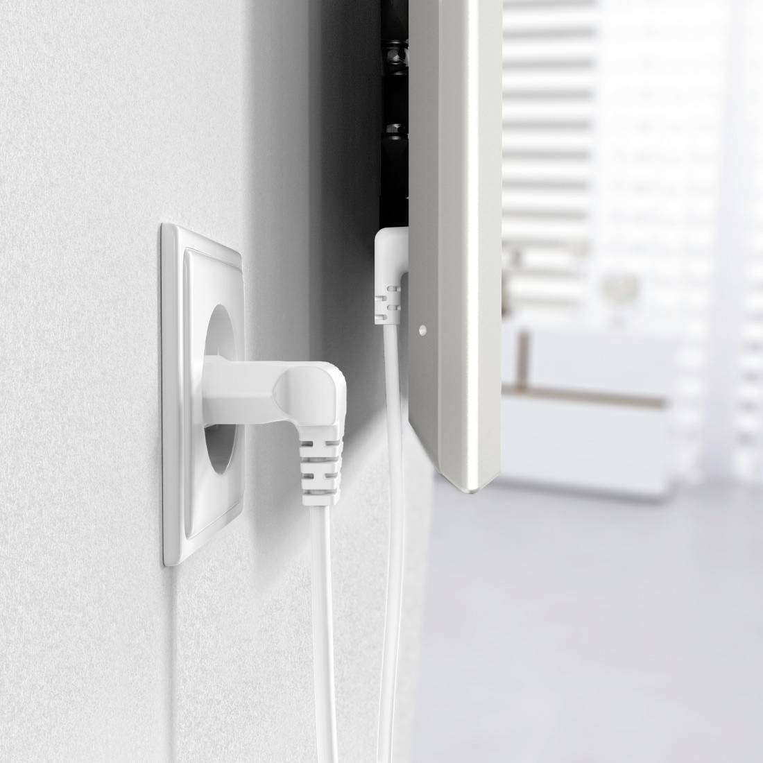 Steckdose mit einem weißen Stecker an der Wand, verbunden mit einem Kabel, das zu einem Gerät führt. Im Hintergrund unscharfes Interieur.