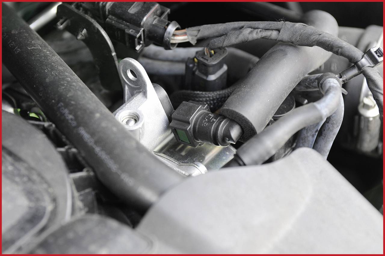 Nahaufnahme eines Automotors, zeigt verschiedene Kabel und Anschlüsse, die miteinander verbunden sind. Hauptsächlich technische Komponenten.