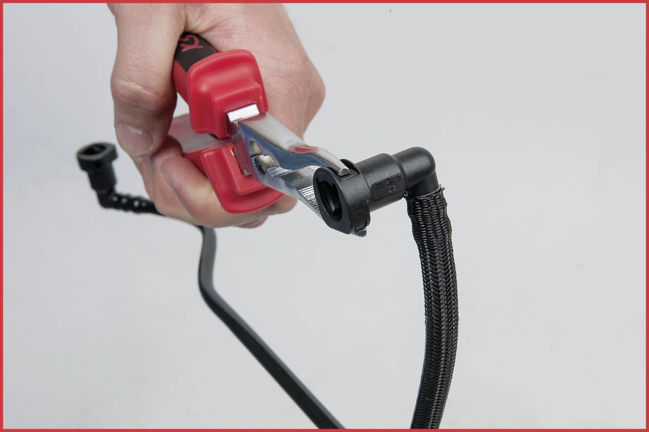 Hand hält ein rotes Starthilfekabel, das an einem schwarzen Kabel befestigt wird.