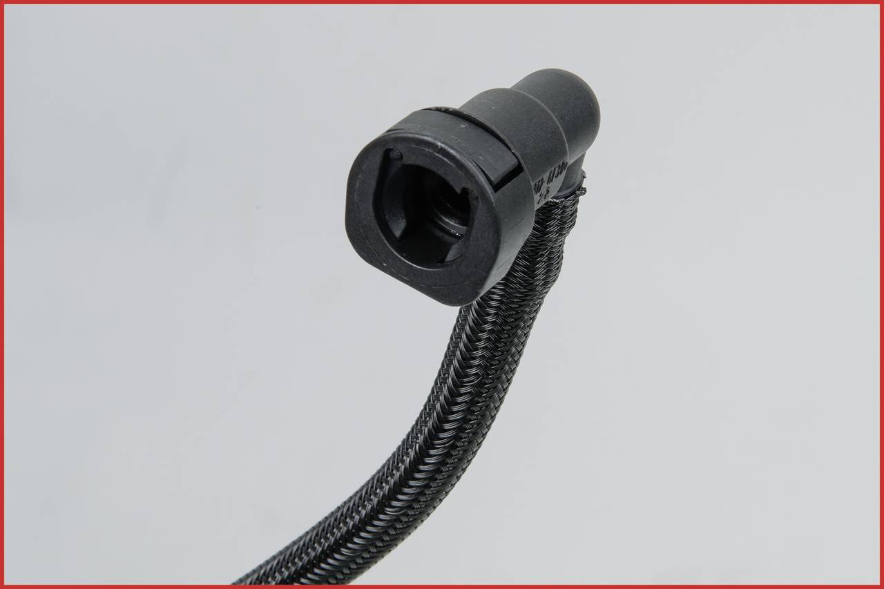 Nahaufnahme eines schwarzen Steckers mit ummanteltem Kabel vor grauem Hintergrund. Der Fokus liegt auf der Struktur und Form des Steckers.