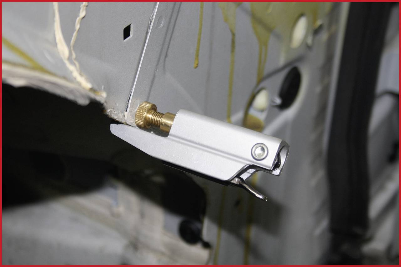 Ein Metallteil mit einem Hebelmechanismus ist an einem Fahrzeugrahmen befestigt. Es scheint ein Einstell- oder Spannmechanismus zu sein.