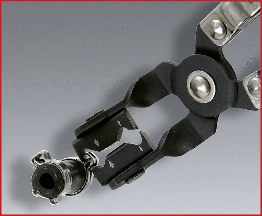 Zange hält eine Metallöse über grauem Hintergrund.