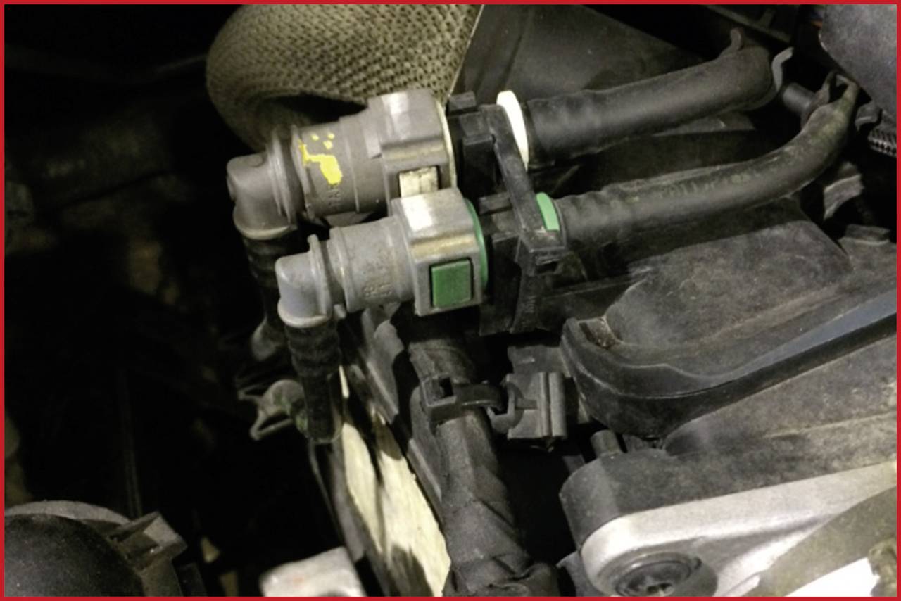 Zwei verbundene Sensoren mit Kabeln in einem Motorraum. Einer hat grüne, der andere gelbe Markierungen. Sie sind in Nahaufnahme sichtbar.