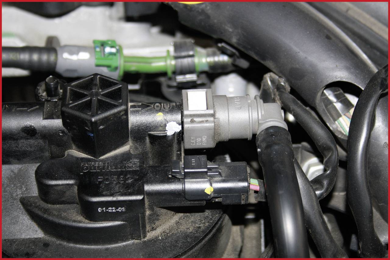 Ein Motorraum mit sichtbaren Schläuchen, Sensoren und Kabeln, die verschiedene Fahrzeugteile verbinden.