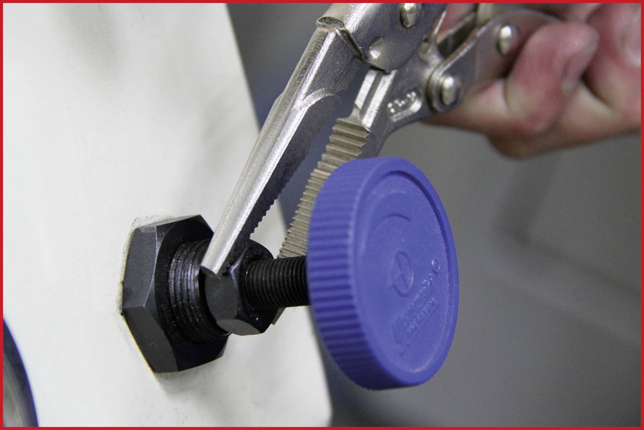 Eine Person benutzt eine Rohrzange, um eine Schraube mit einem blauen Kunststoffkopf zu drehen, der an einem metallischen Gewinde befestigt ist.