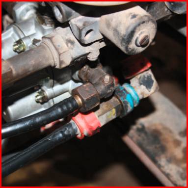 Nahaufnahme von hydraulischen Anschlüssen an einer Maschine, mit mehreren Schläuchen und Steckverbindungen. Verschiedene Farben kennzeichnen die Verbindungen.