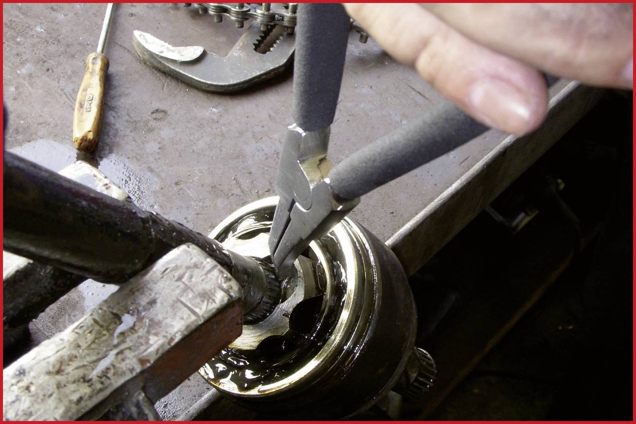 Eine Person repariert eine Maschinenteilkupplung mit Zange auf einer Werkbank, umgeben von verschiedenen Werkzeugen.