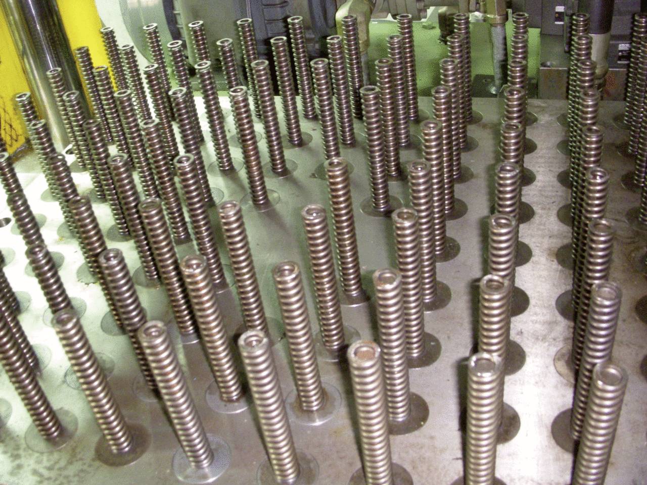 Metallfedern in Reihen auf einer industriellen Maschine, möglicherweise Teil eines Herstellungsprozesses.