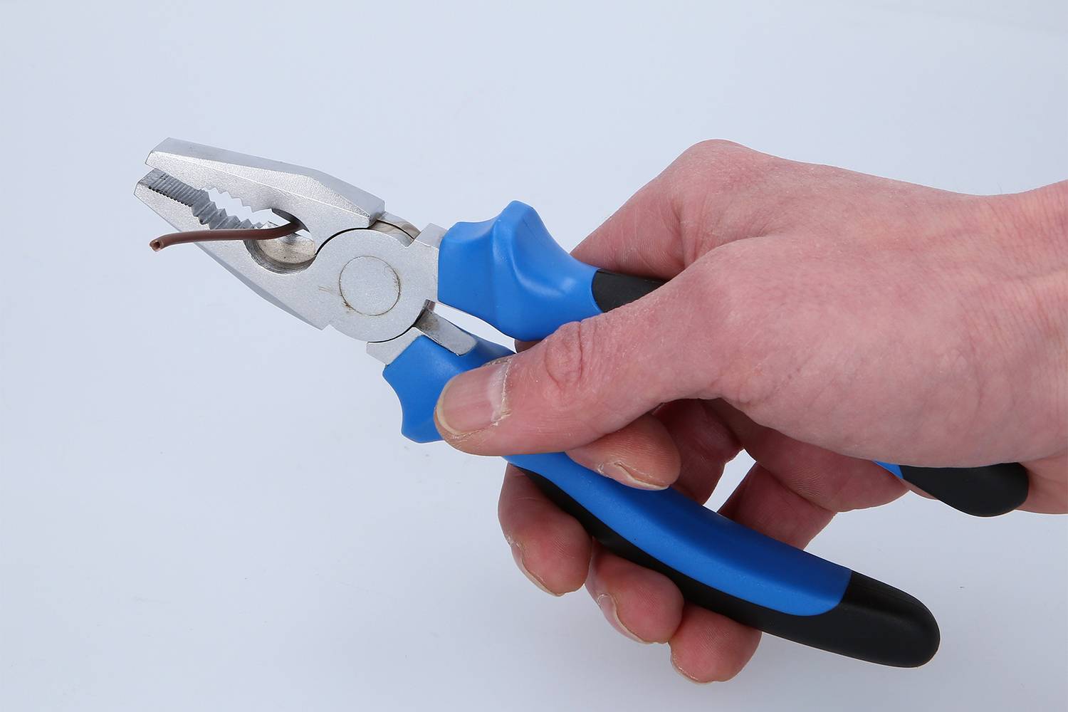 Eine Hand hält eine blaue Zange und biegt damit einen dünnen Draht.