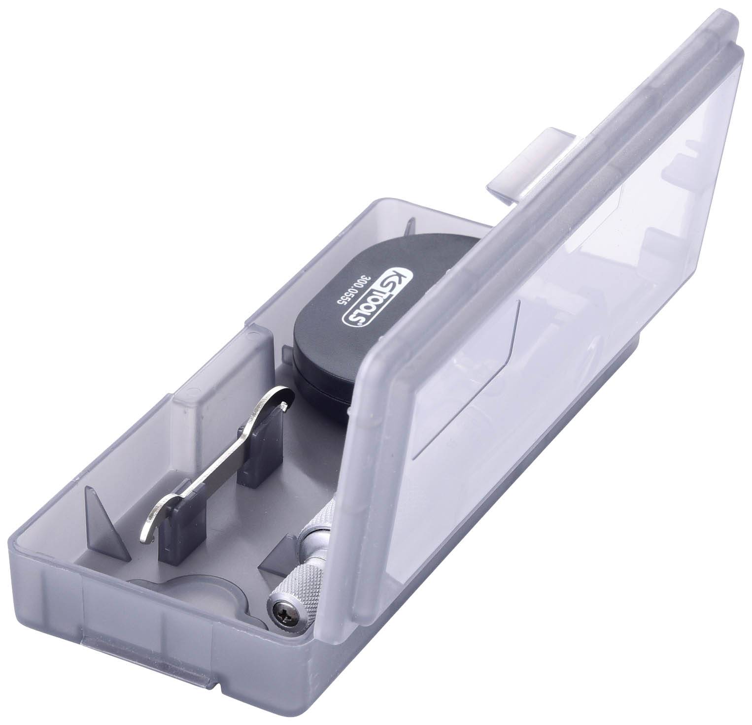 Geöffnete transparente Plastikbox mit einem Stimmgerät, einer Metallklammer und zwei kleinen zylinderförmigen Objekten.