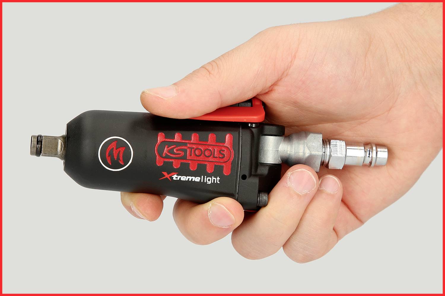 Hand, die ein schwarzes KS Tools Druckluftwerkzeug mit roter Aufschrift 'Xtreme light' hält. Es ist ein kompaktes Gerät mit Anschluss.