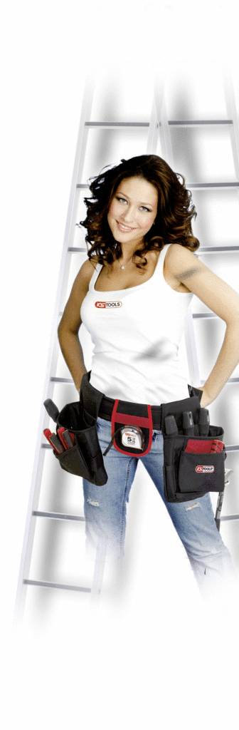 Frau mit langem, lockigem Haar steht vor einer Leiter. Sie trägt eine Werkzeugtasche um die Taille und ein weißes Oberteil.