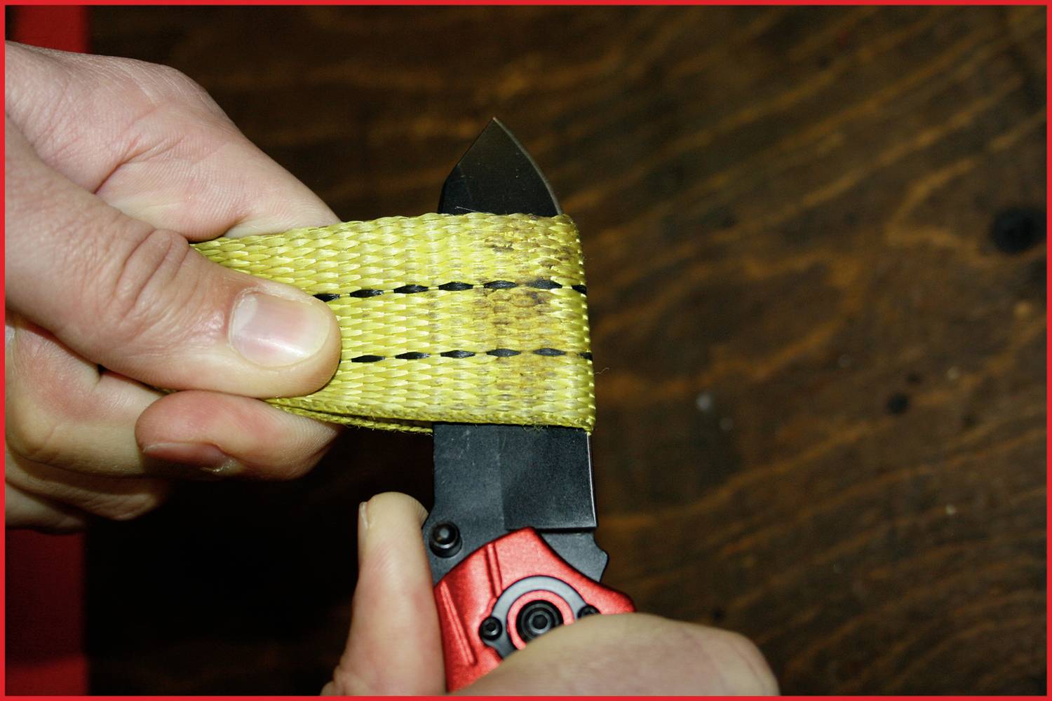 Eine Person schneidet mit einem Messer durch ein robustes, gelbes Band. Das Band hat schwarze Streifen und der Hintergrund ist aus Holz.