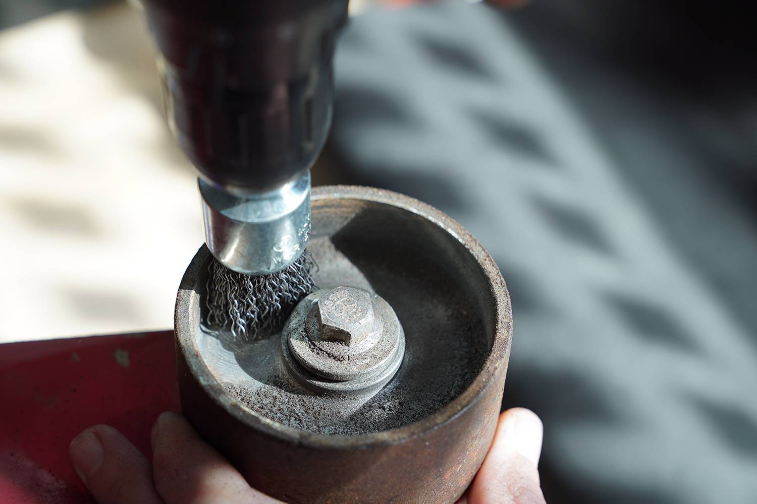 Eine Metallbürste, die an eine Bohrmaschine angebracht ist, reinigt die Innenseite eines zylindrischen Metallgegenstands.