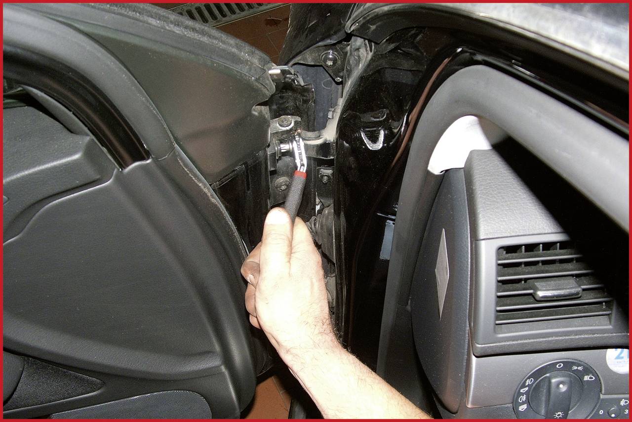 Eine Hand hält ein Schraubenwerkzeug und befestigt ein Autoteil im Innenraum.
