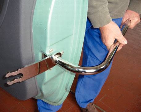 Person montiert Metallgriff an grünes Gerät, zeigt Werkzeugarbeit.