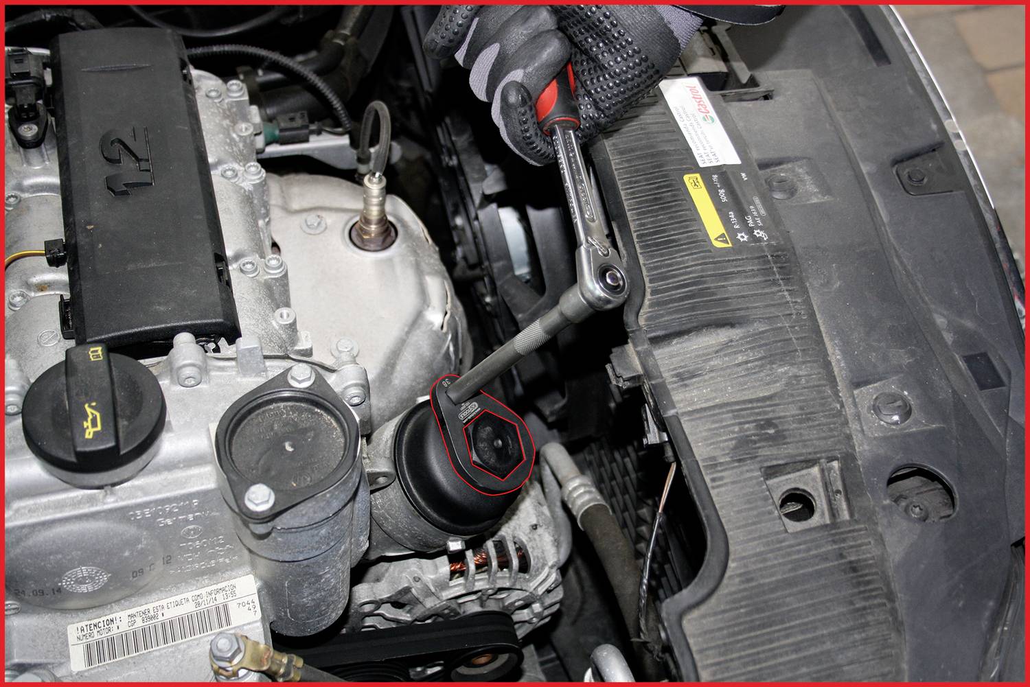 Person bedient mit einem Schraubenschlüssel den Ölfilterdeckel eines Autos im Motorraum. Angespanntes Arbeiten an Fahrzeugmotor.