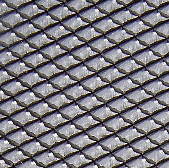 Nahaufnahme einer gleichmäßigen, schuppenartigen Textur einer Fischhaut mit silbernen und grauen Tönen, die ein sich wiederholendes Muster bildet.
