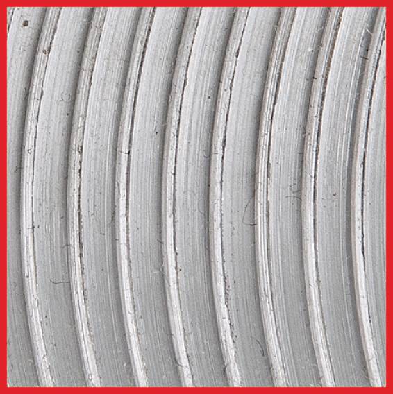 Nahaufnahme von silbernen, konzentrischen Rillen auf einer Metalloberfläche mit einem roten Rahmen.