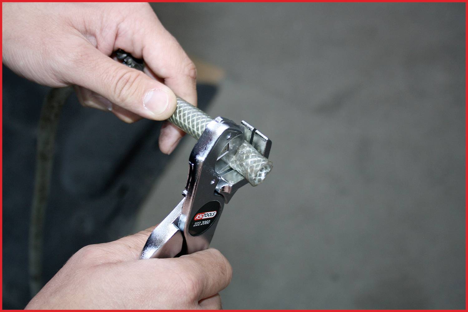 Person schneidet ein geflochtenes Kabel mit einem Metallwerkzeug. Hände im Vordergrund konzentrieren sich auf den präzisen Schnitt.