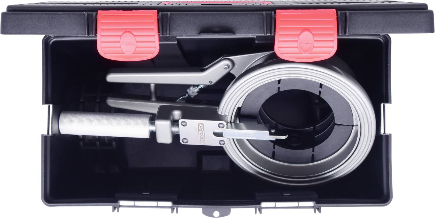 Eine offene Werkzeugkiste, die ein Gerät mit silbernem Griff und einem flachen, aufgerollten Band enthält, von oben betrachtet.