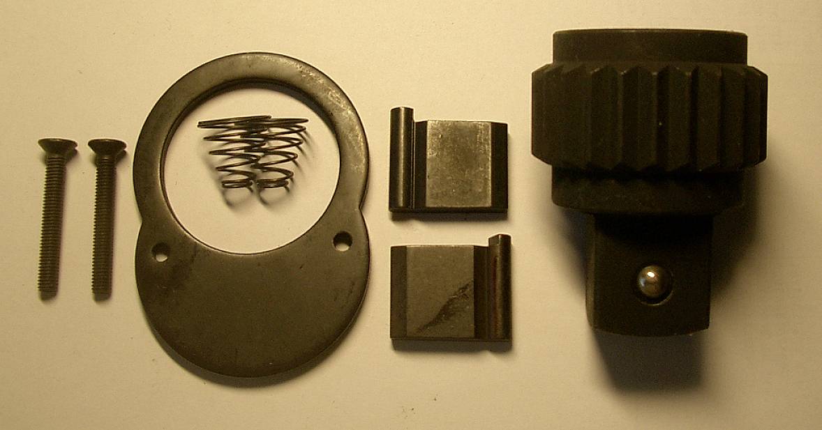 Ein Satz Autoteile: zwei Schrauben, eine Feder, zwei Metallklemmen, ein runder Ring und ein schwarzes zylindrisches Bauteil.