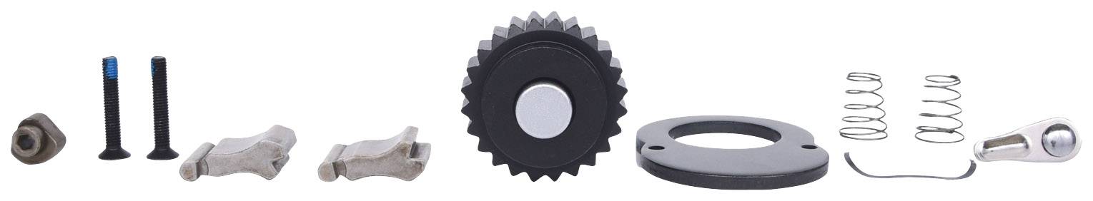 Einzelteile eines Maschinengetriebes, darunter Zahnräder, Federn und Schrauben, aufgereiht auf einer weißen Fläche.