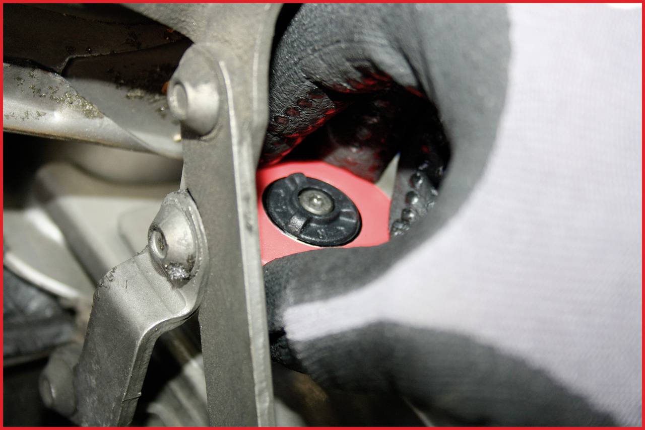 'Hand in Handschuh dreht rote Kappe an einem mechanischen Gerät'.