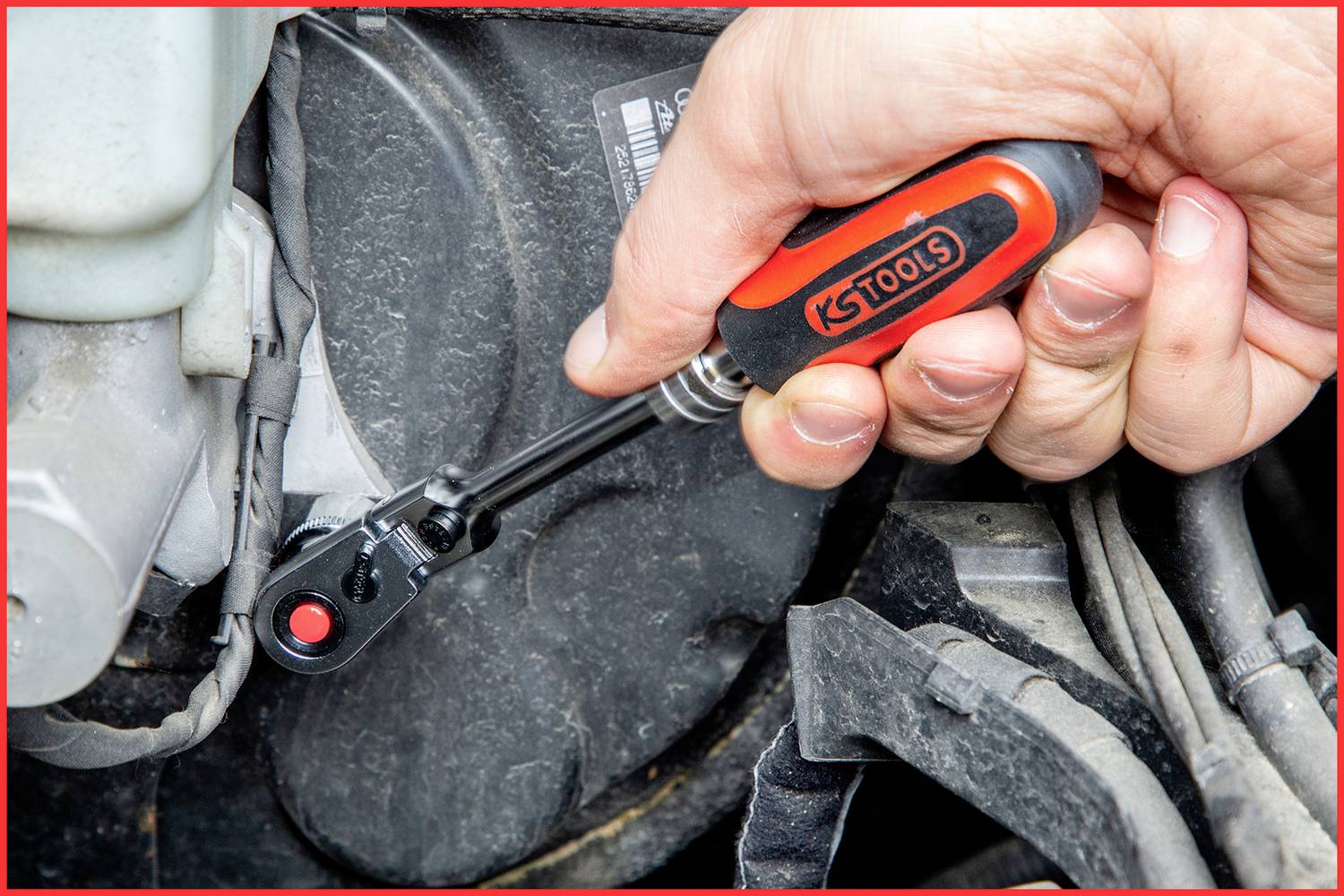 Eine Hand benutzt einen Schraubenschlüssel, um eine Schraube an einem Autoteil festzuziehen.