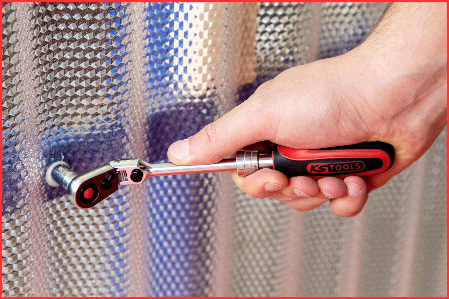 Eine Hand benutzt einen Ratsche-Schraubendreher, um eine Schraube an einer strukturierten Metalloberfläche anzuziehen.