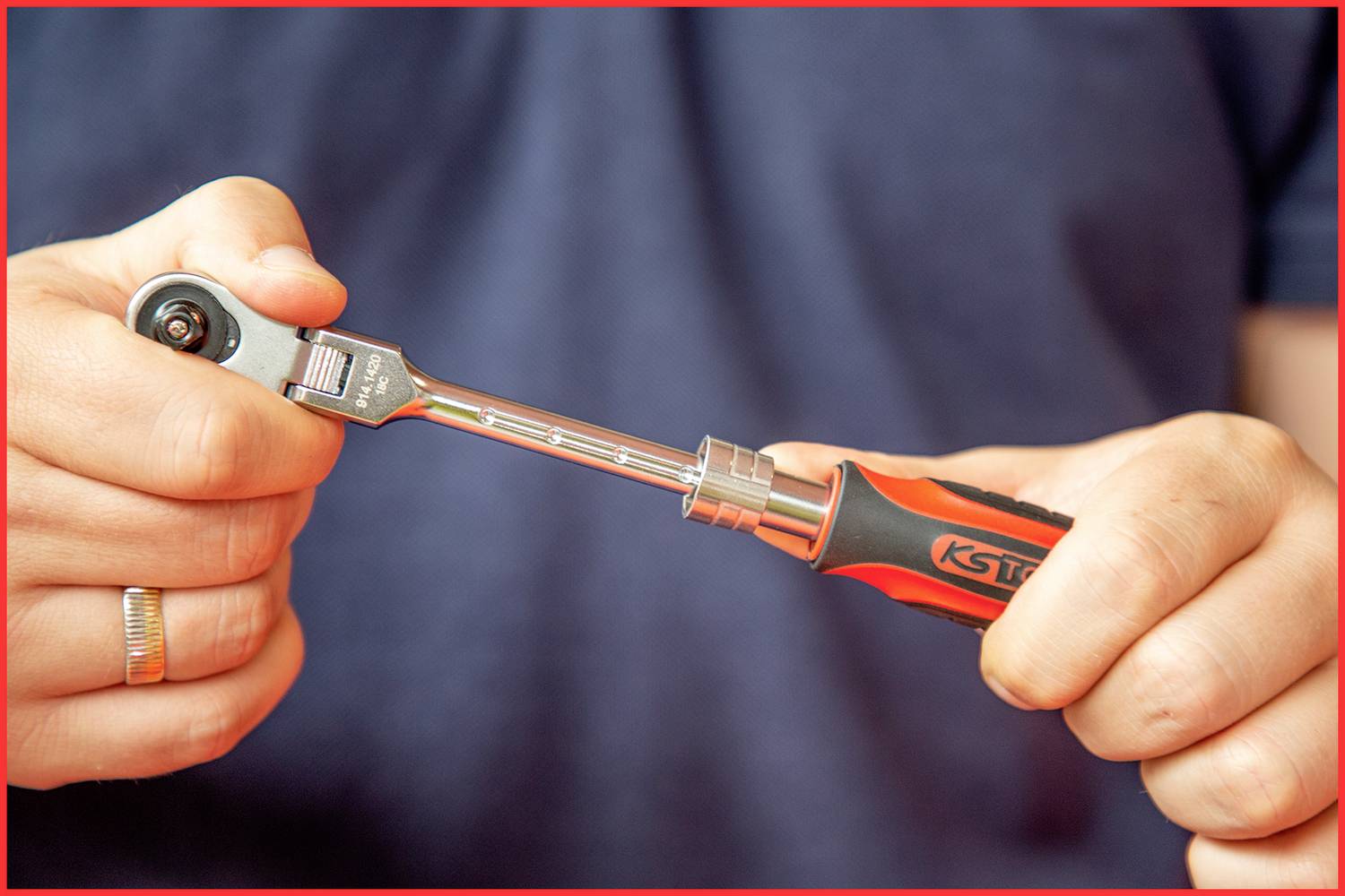 Person hält einen Ratschen-Schraubenschlüssel. Die Hände sind fokussiert, während der Hintergrund unscharf ist.