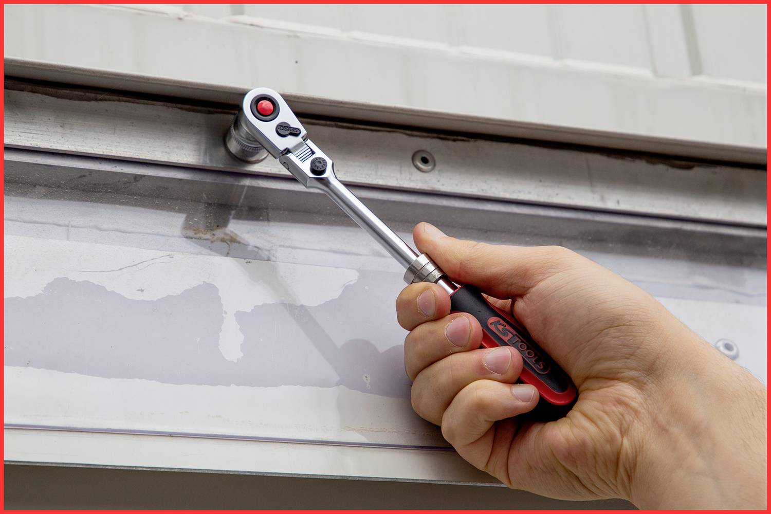 Eine Hand hält einen Steckschlüssel und dreht eine Schraube an einer Metallplatte.