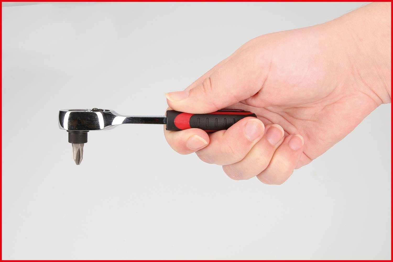 Eine Hand hält eine Ratsche mit einem schwarzen Griff und einem Bitaufsatz.