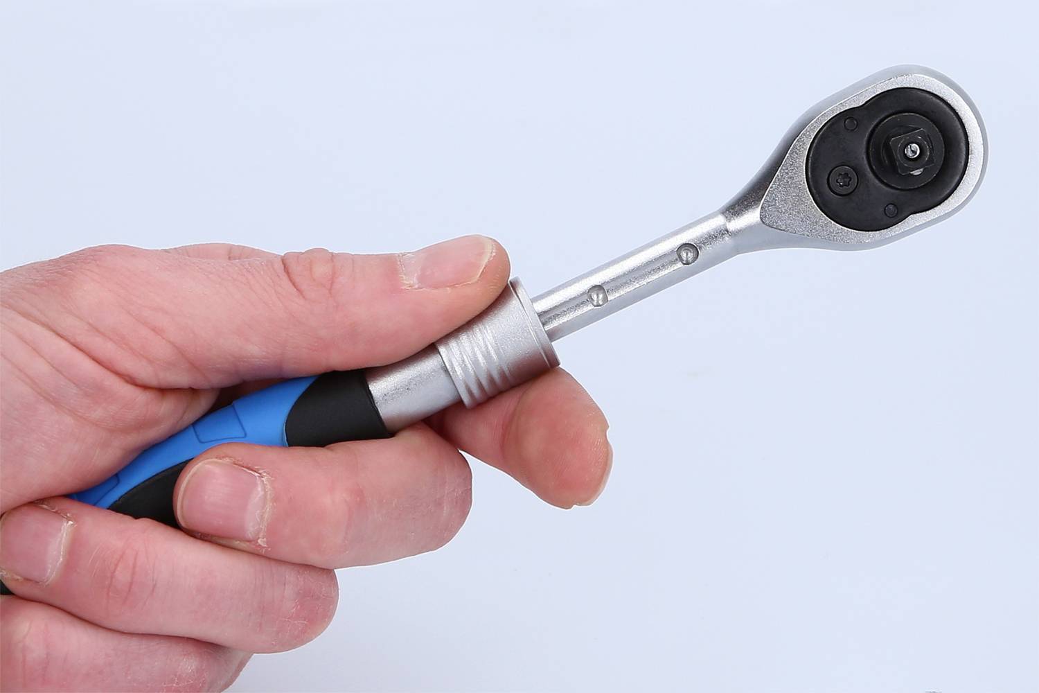 Eine Hand hält einen kleinen, silbernen Ratschen-Schraubenschlüssel mit schwarzem und blauem Griff vor einem weißen Hintergrund.