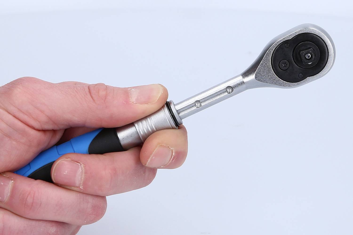 Eine Hand hält einen Ratschen-Schraubenschlüssel mit blauem Griff, verwendet zum Festziehen von Schrauben und Muttern.