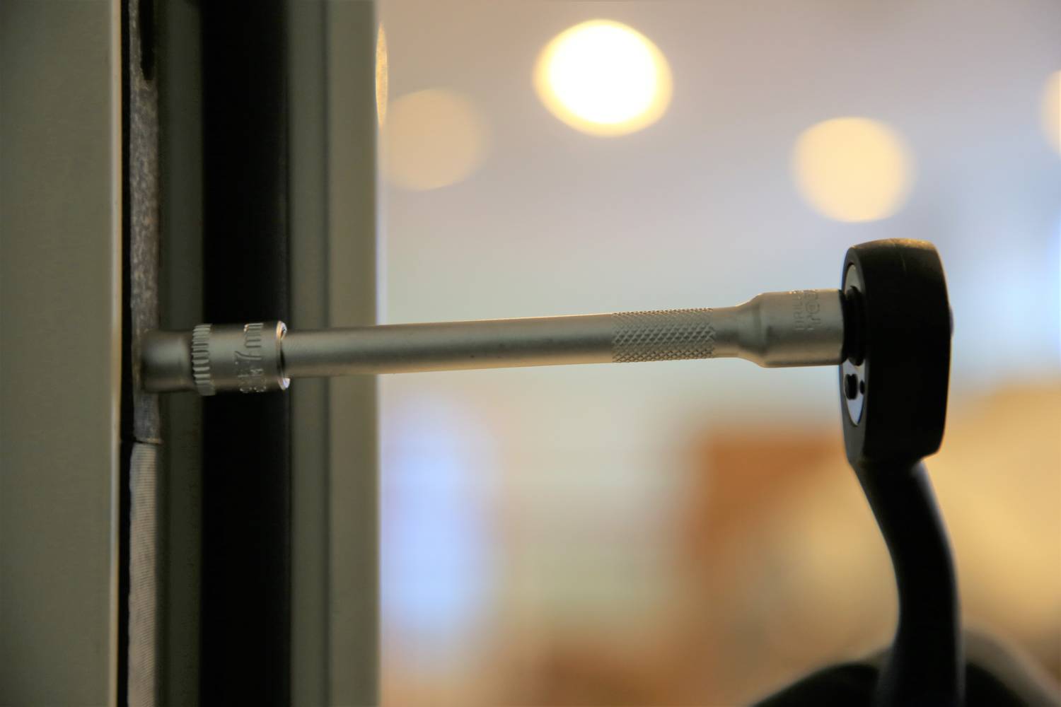 Ein Schraubendreher, der eine Schraube in eine Tür einzieht. Der Hintergrund ist unscharf mit einigen leuchtenden Punkten.