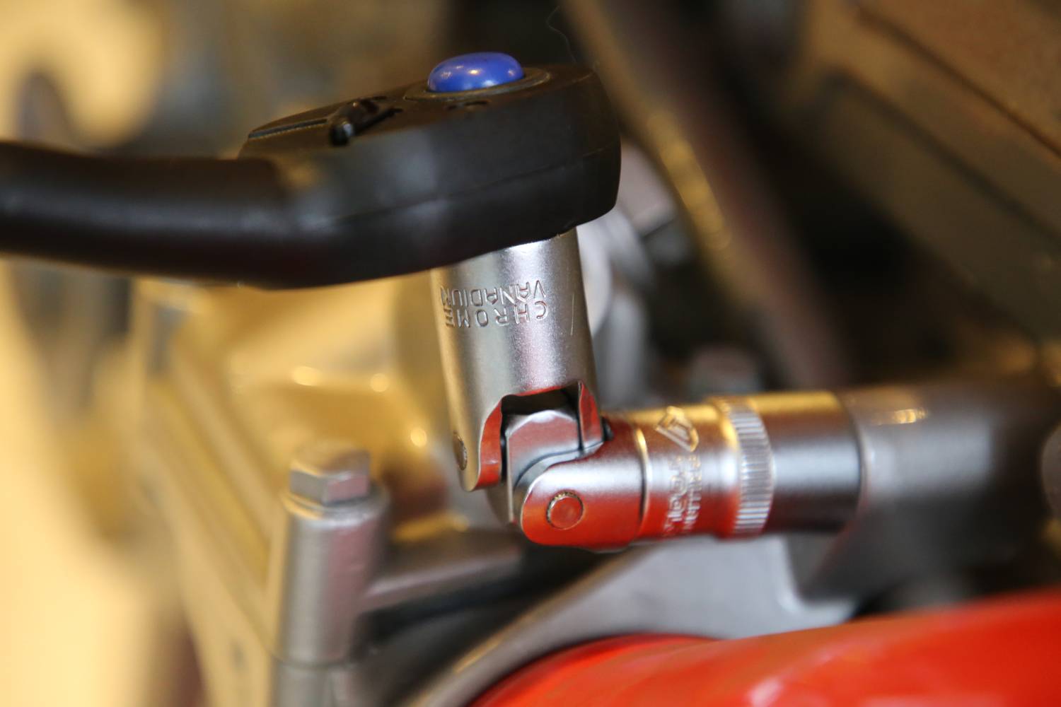 Ein silberfarbener Drehmomentschlüssel mit einer blauen Taste wird verwendet, um eine Schraube an einer metallischen Vorrichtung zu befestigen.