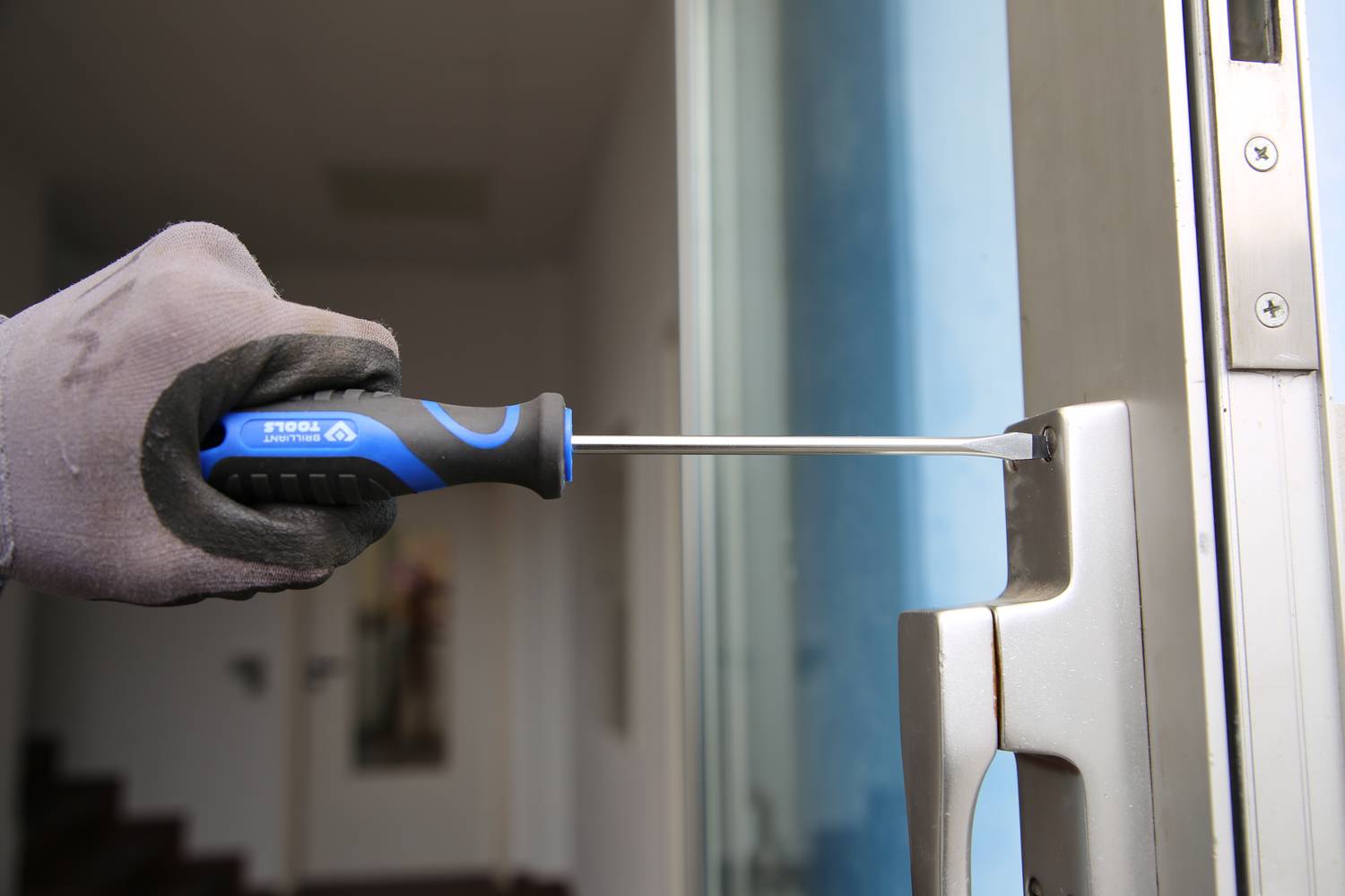 Person schraubt mit einem Schraubendreher eine Schraube in einem Türschloss fest.zeigt, wie man ein Türschloss repariert oder installiert.