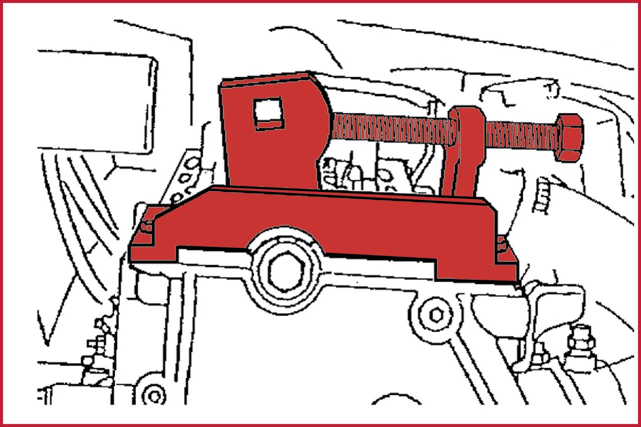 Eine rote mechanische Vorrichtung mit Schraubmechanismus ist auf einem Motorblock montiert, möglicherweise ein Werkzeug zum Spannen oder Fixieren.