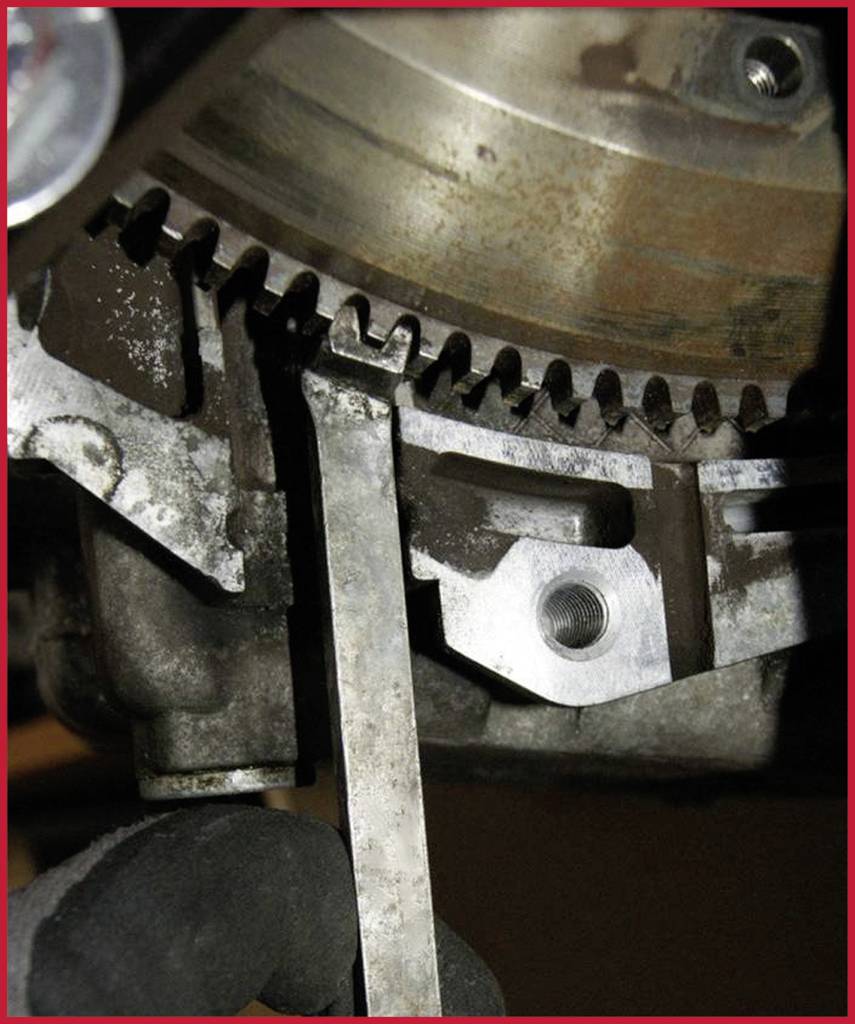 Ein Mechaniker misst den Abstand zwischen einem Zahnrad und einer Metalllehre an einem Motor, um präzise Einstellungen vorzunehmen.