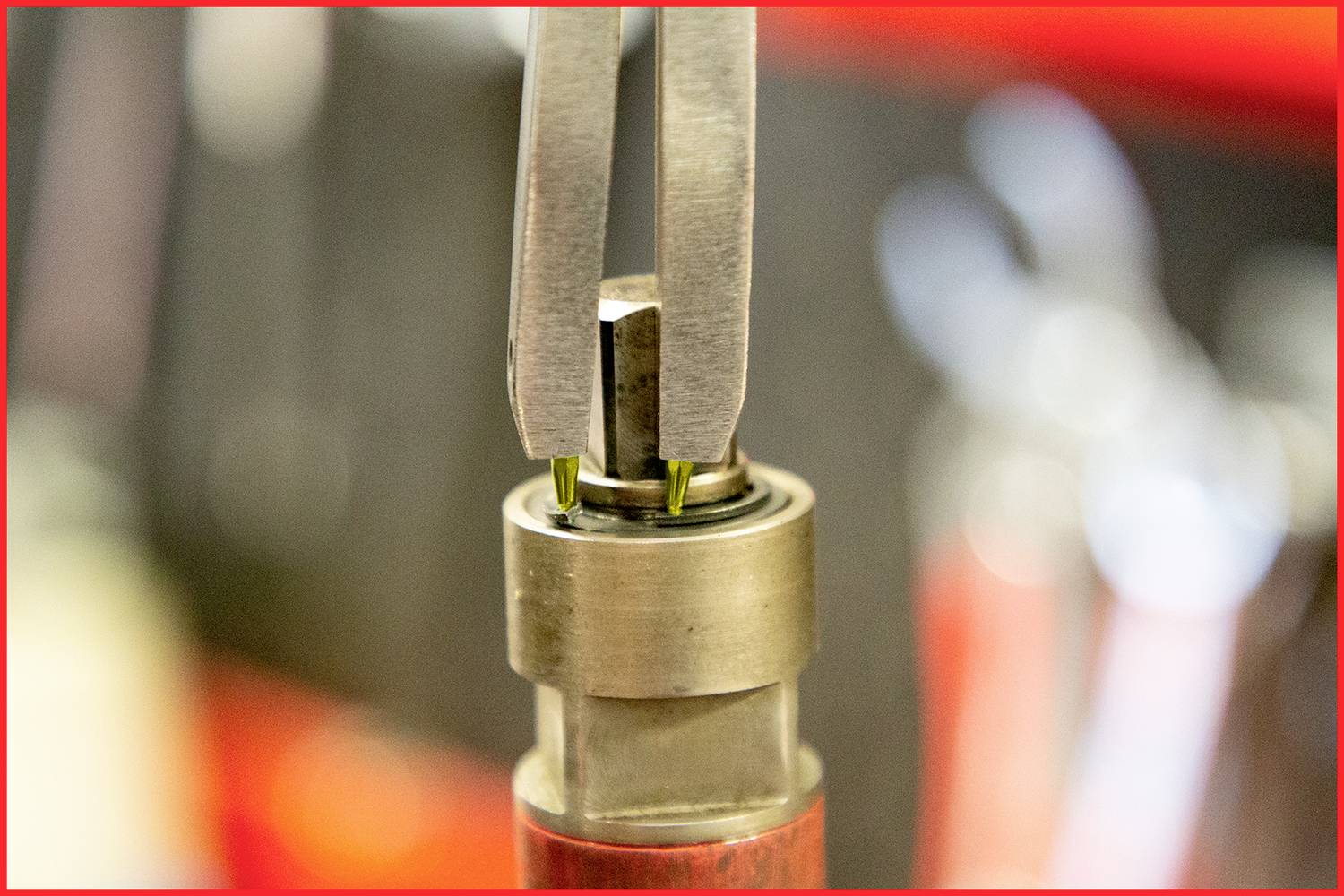 Nahaufnahme eines mechanischen Werkzeugs, das einen Schraubverschluss bearbeitet. Der Hintergrund ist unscharf und rot umrandet.