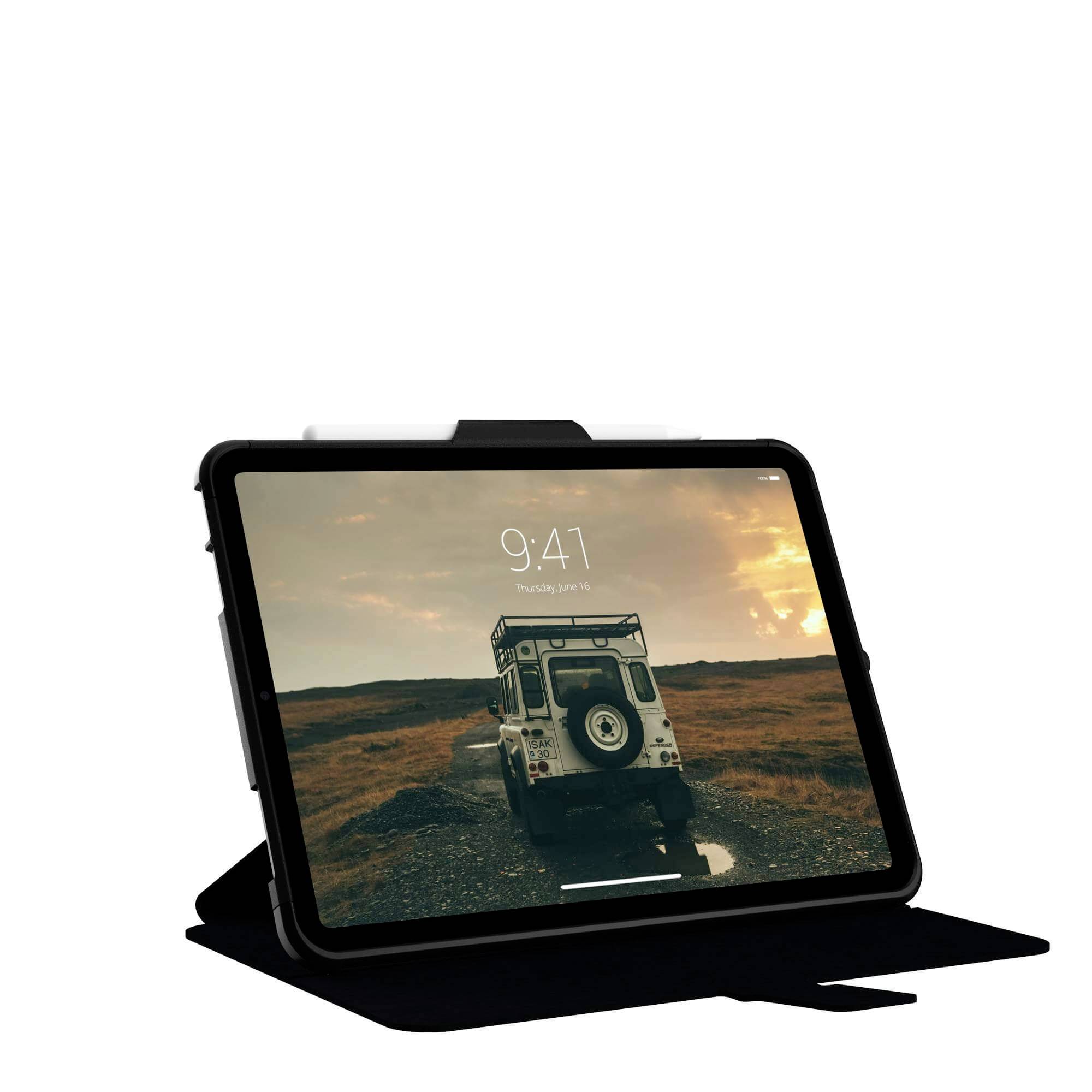 Tablet im Querformat zeigt Foto von Geländewagen auf unbefestigtem Weg in ländlicher Landschaft bei Sonnenuntergang.
