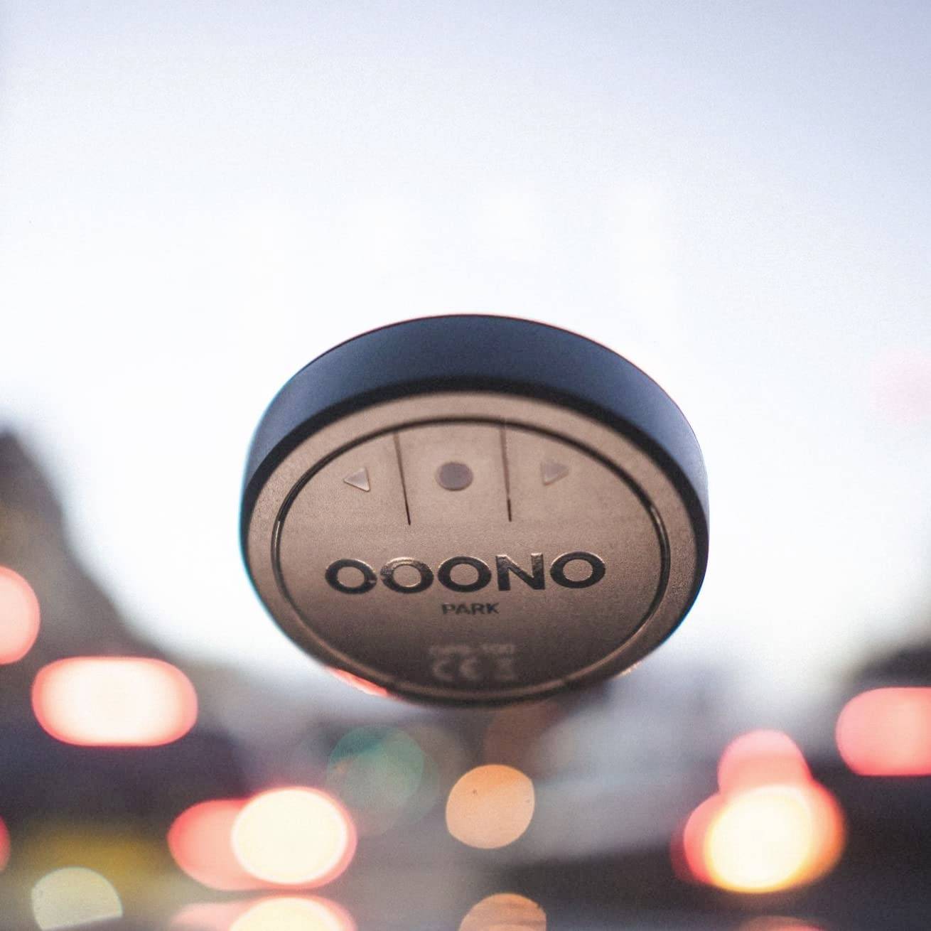 Ein rundes elektronisches Gerät mit der Aufschrift 'OONO' ist an einer Windschutzscheibe befestigt, mit verschwommenen Lichtern im Hintergrund.