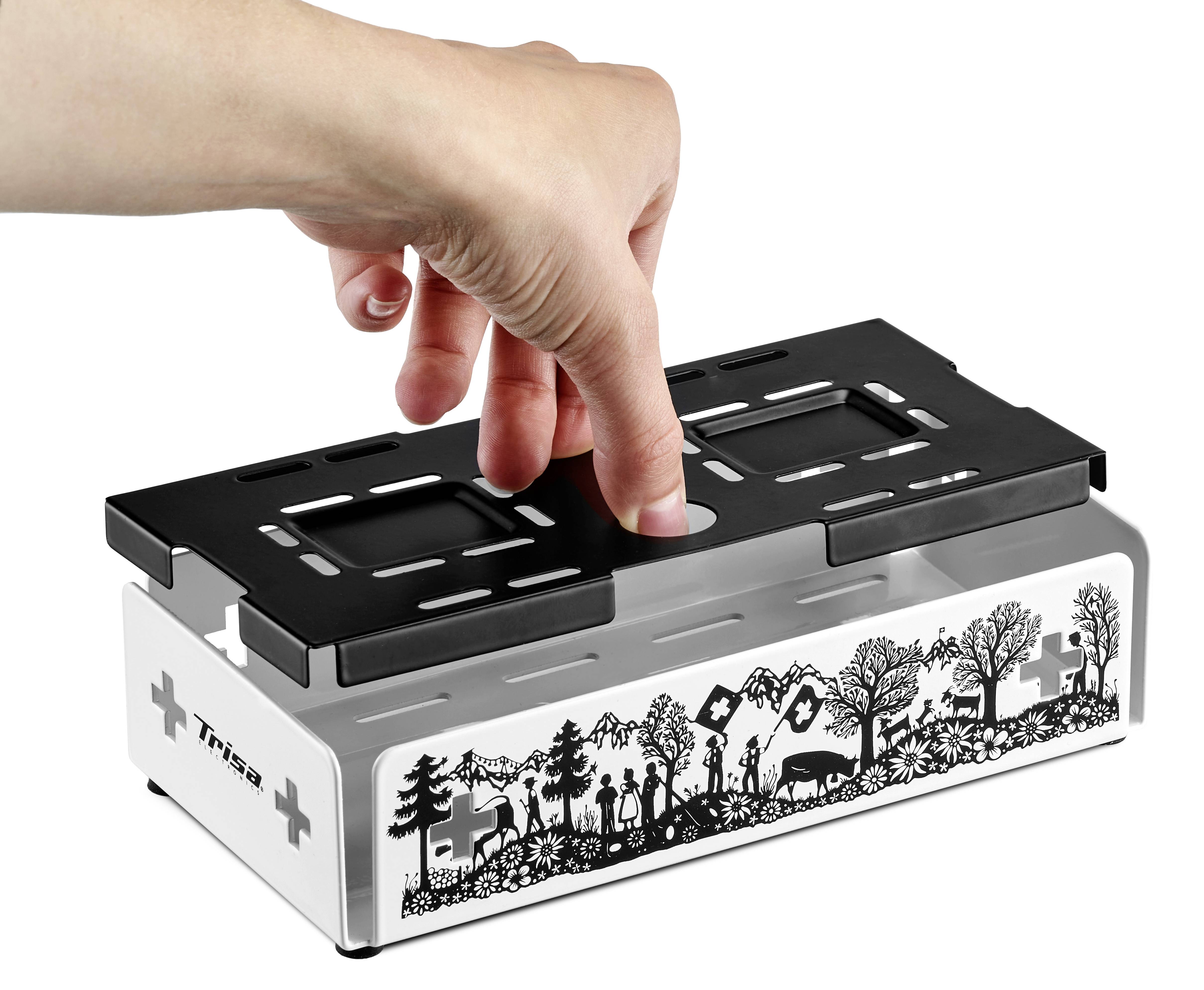 Eine Hand legt einen schwarzen Einsatz in einen Toaster ein. Der Toaster zeigt ein schwarzes Wald- und Tiermotiv auf weißem Hintergrund.