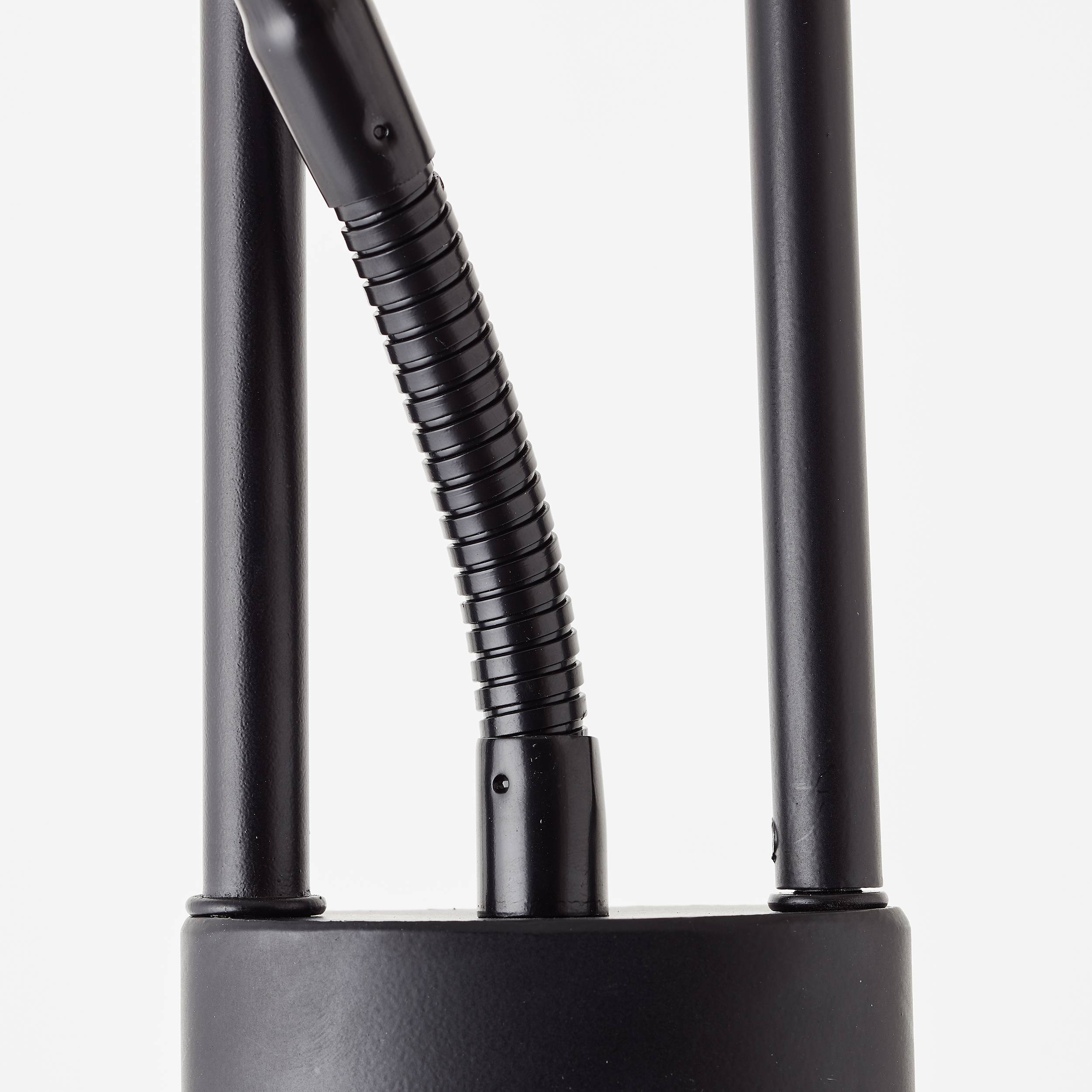 Schwarzes, zylindrisches Objekt mit zwei vertikalen Stangen und flexibler Verbindung in der Mitte. Minimalistisches, modernes Design.