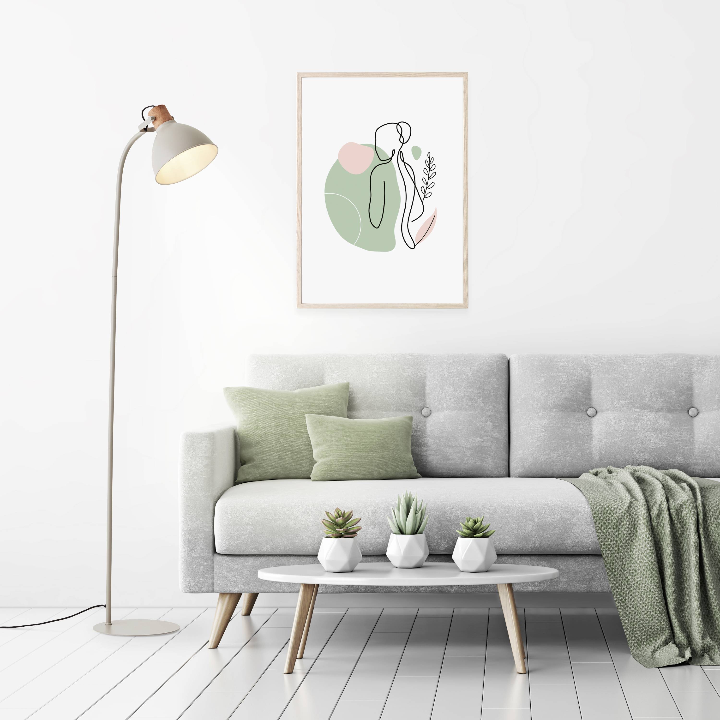 Modernes Wohnzimmer mit grauem Sofa, grünem Kissen und Decke, hellem Holz-Couchtisch, Stehlampe und abstraktem Wandbild.