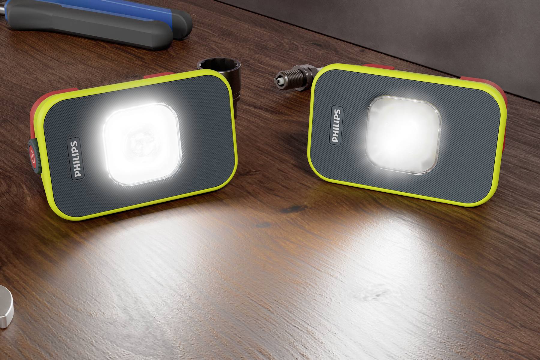 Zwei tragbare LED-Leuchten von Philips mit leuchtendem weißen Licht auf einem Holztisch. Sie haben ein modernes, robustes Design.