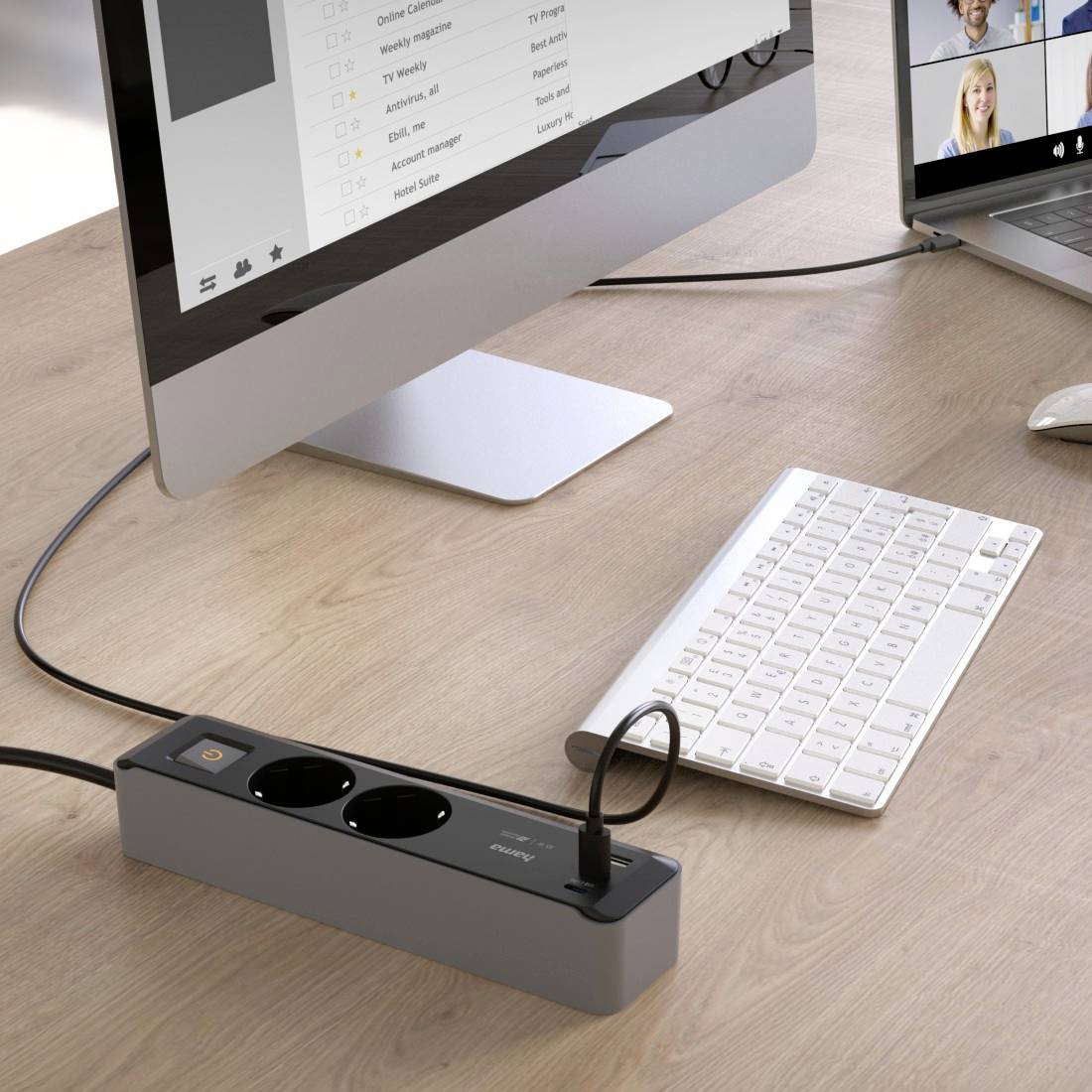 Ein Schreibtisch mit einem Computer, einer Tastatur und einer Steckdosenleiste mit zwei Steckdosen und einem USB-Anschluss.