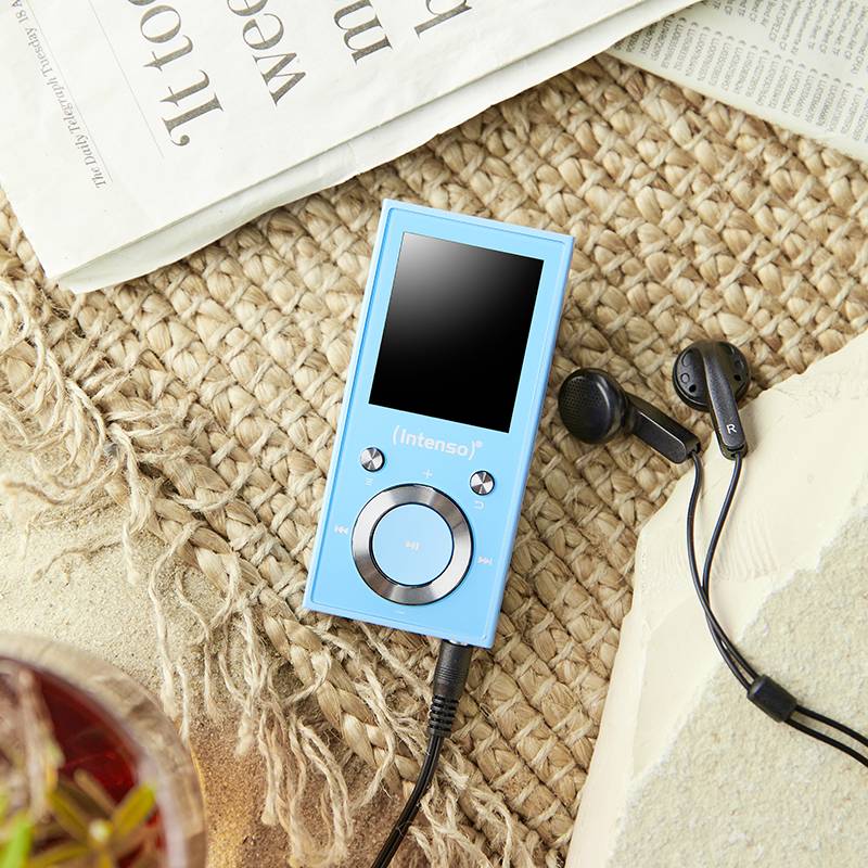 Ein blauer MP3-Player der Marke 'Intenso' liegt auf einem geflochtenen Untergrund, daneben schwarze Ohrhörer und eine gefaltete Zeitung.